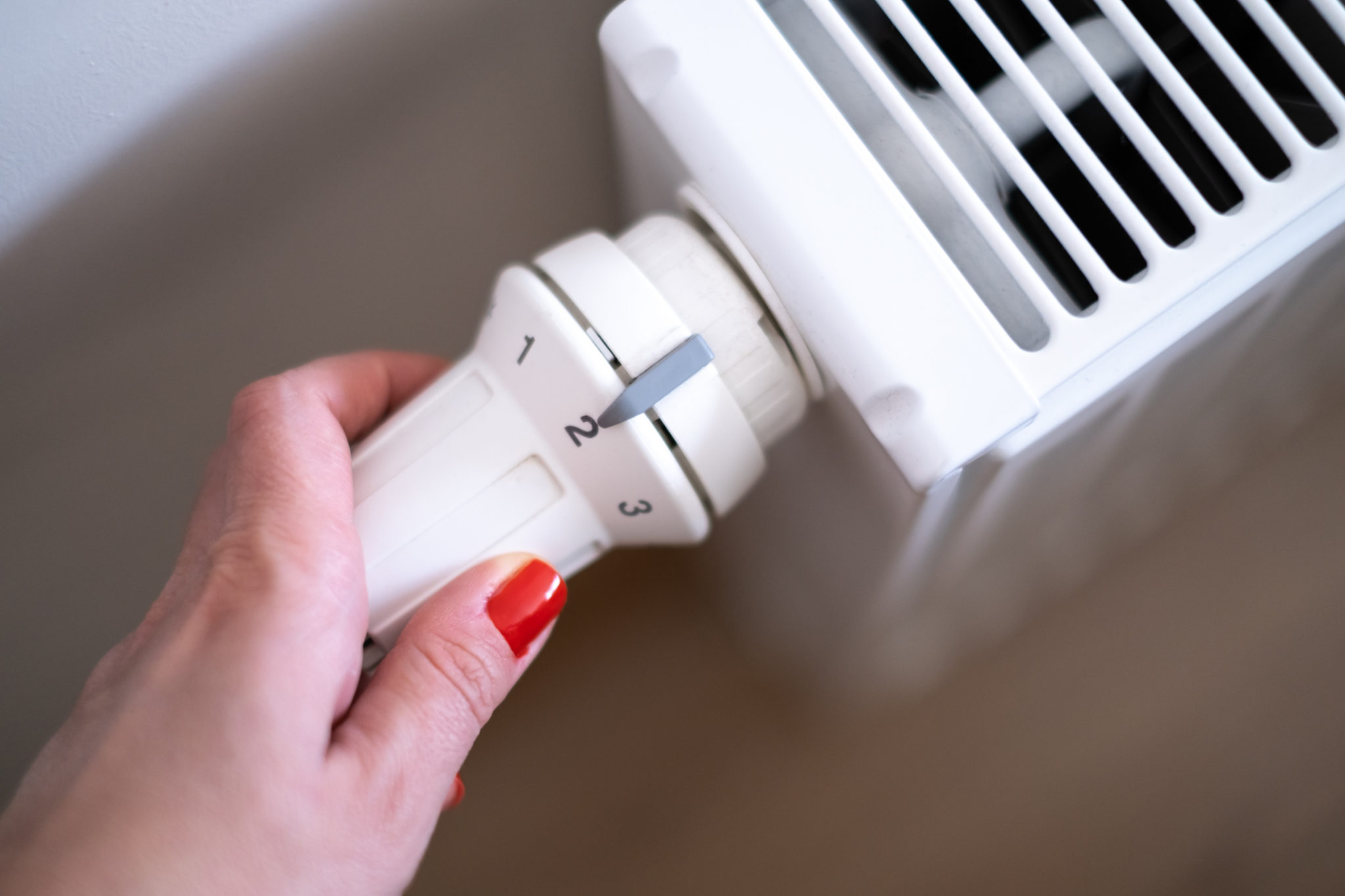Woman's hand adjusting the thermostatic valve of the natural gas heater in room